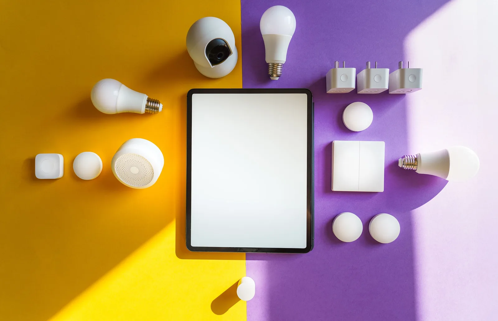 Top view of smart home devices and tablet on split yellow and purple background. Bilingual smart home interfaces, French-language support in Canadian yard tech
