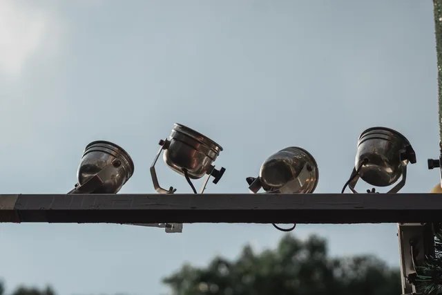 A row of stainless steel spot lights mounted outdoors with a clear blue sky backdrop. Coastal Fog Outdoor Smart Lighting: Fog and Fixture Design